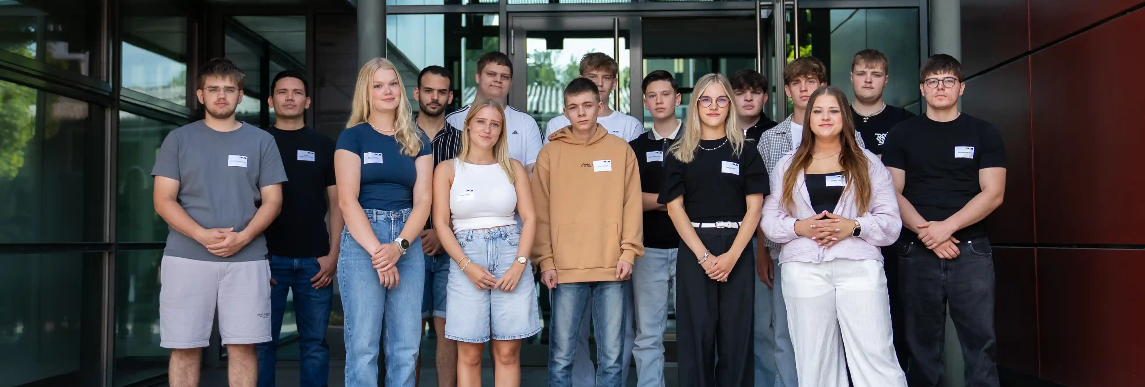 Gruppenfoto der neuen ALHO Auszubildenden vor dem Eingangsbereich eines Bürogebäudes