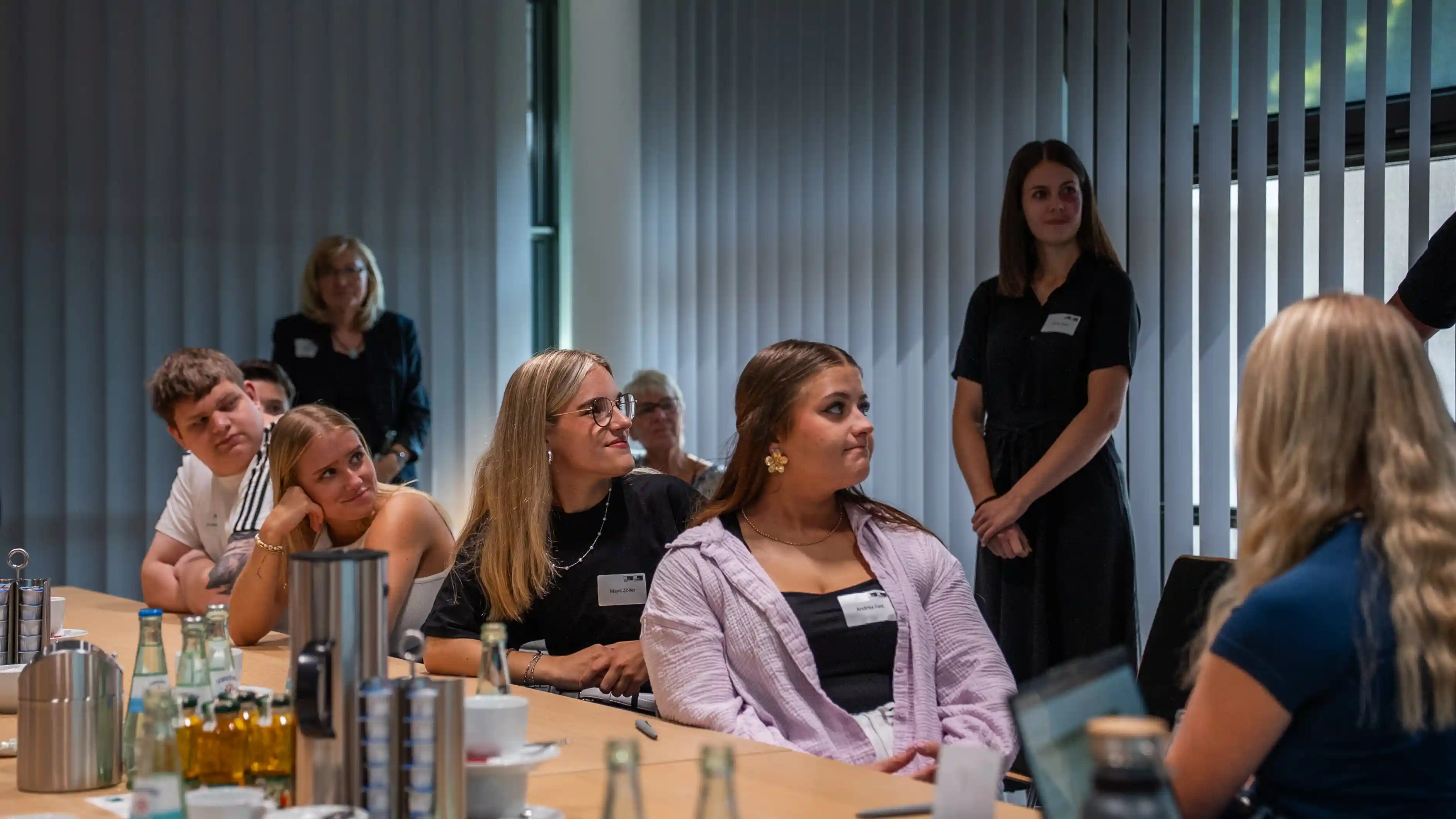 Auszubildende sitzen an einem langen Konferenztisch und hören einer Präsentation zu