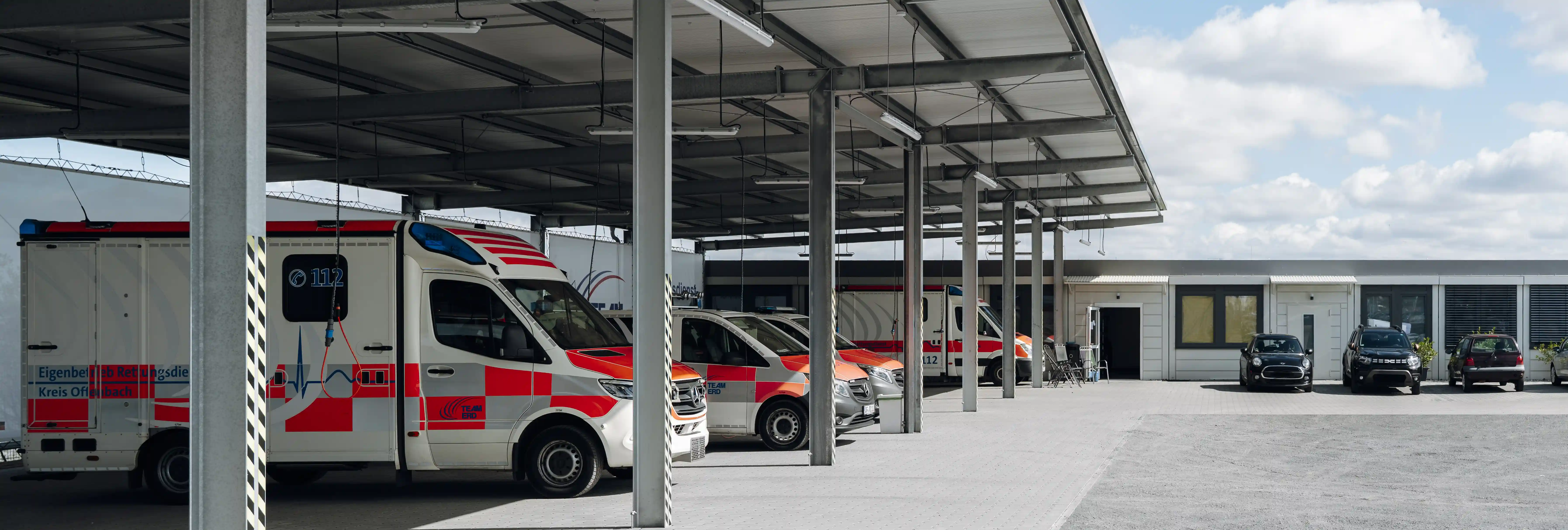 Überdachte Fahrzeughalle einer Rettungswache des Kreises Offenbach mit mehreren geparkten Rettungswagen unter einem Stahlvordach